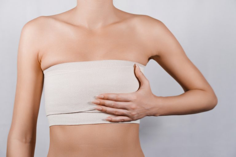 Breast area with surgical dressings following breast lift surgery, illustrating typical mastopexy scarring